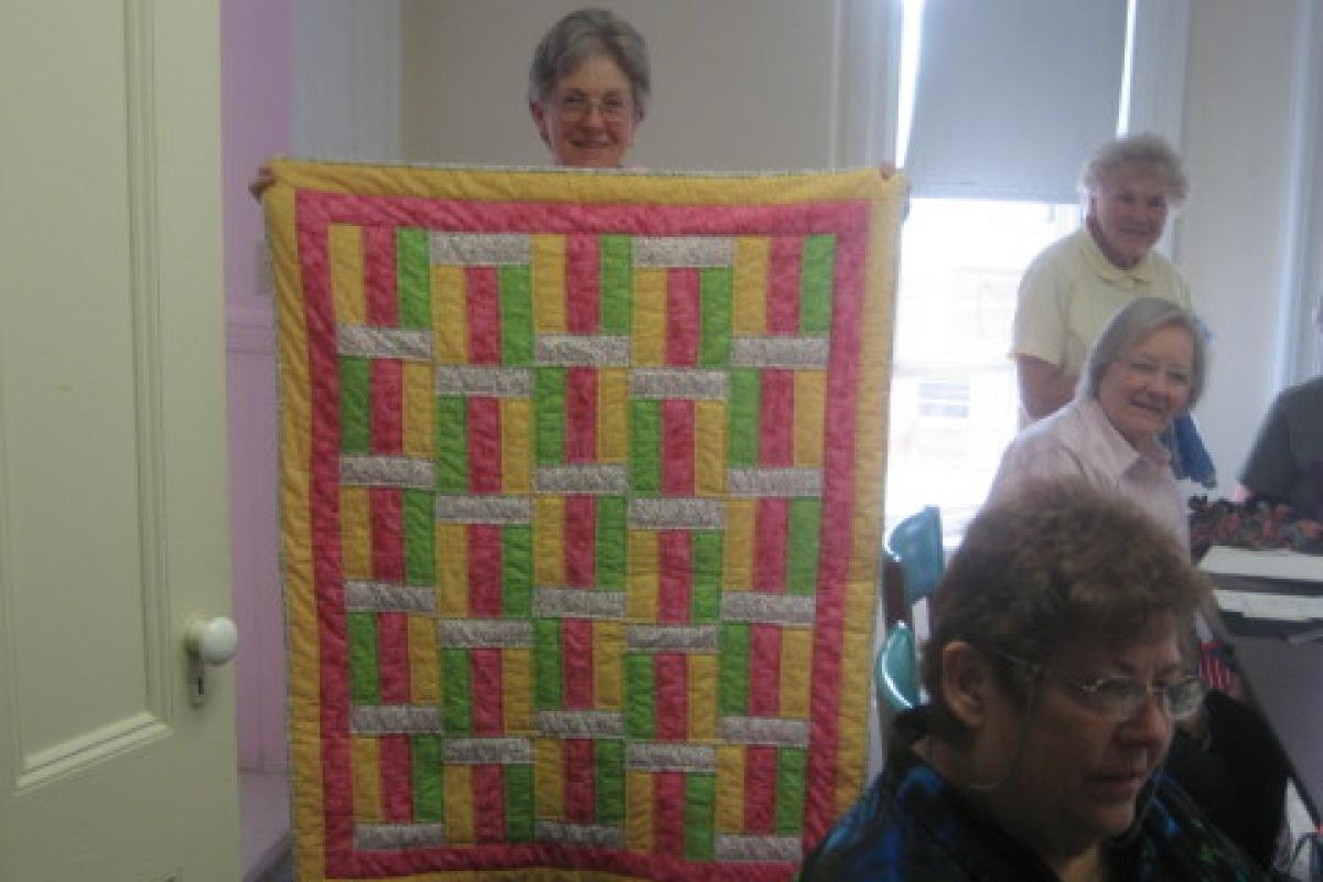 Woman Holding Yellow, Pink, and Green Quilt
