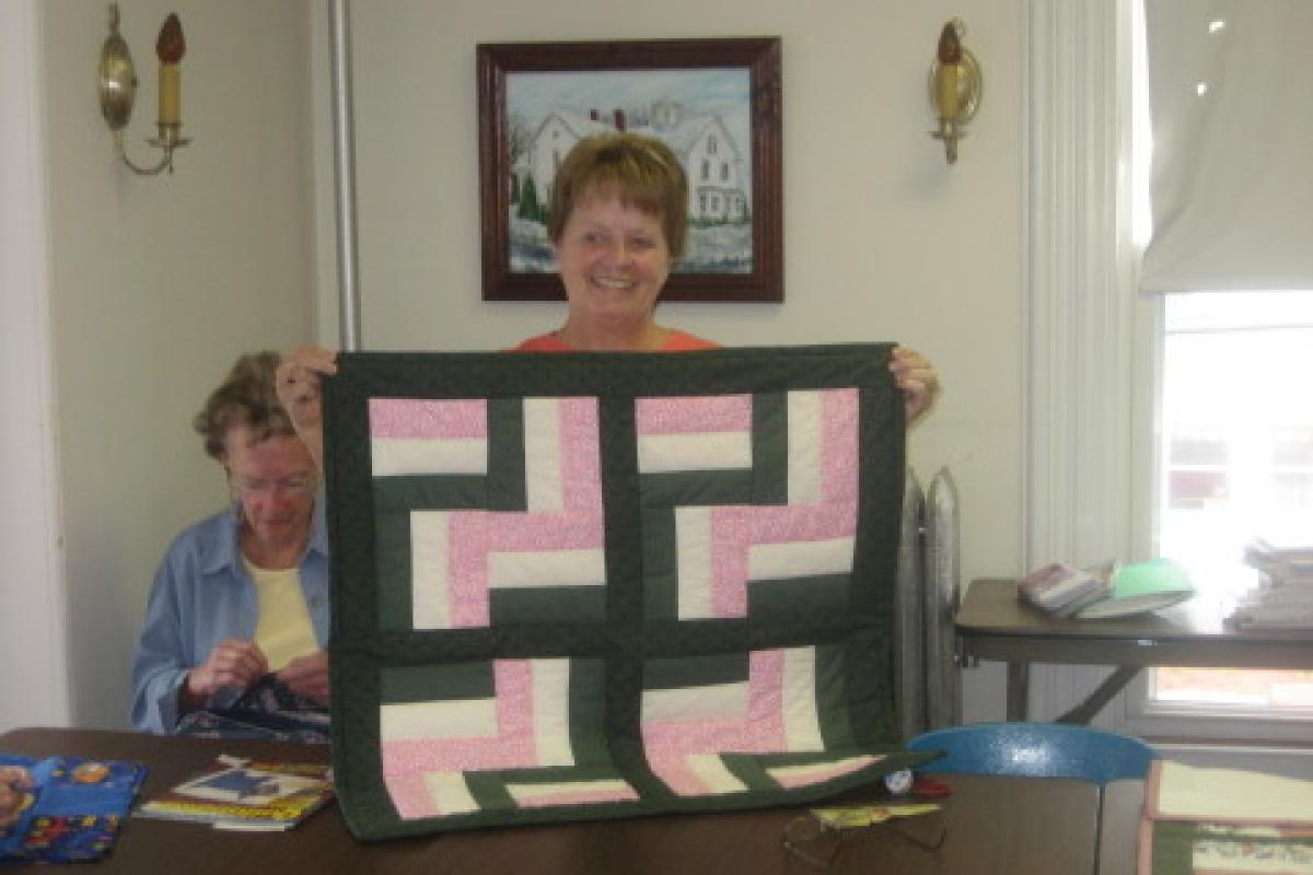 Woman Holding Green, Pink, and White Quilt