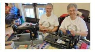 Women Sitting at Table with Sewing Machines